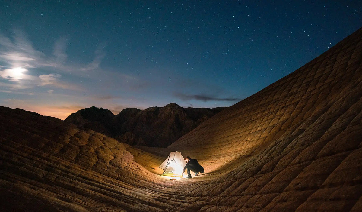 Person setting up tent at night