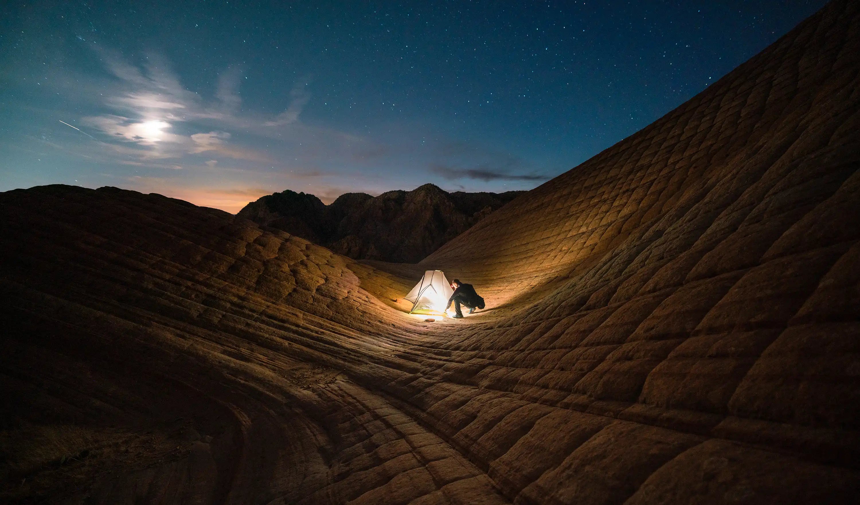 Person setting up tent at night