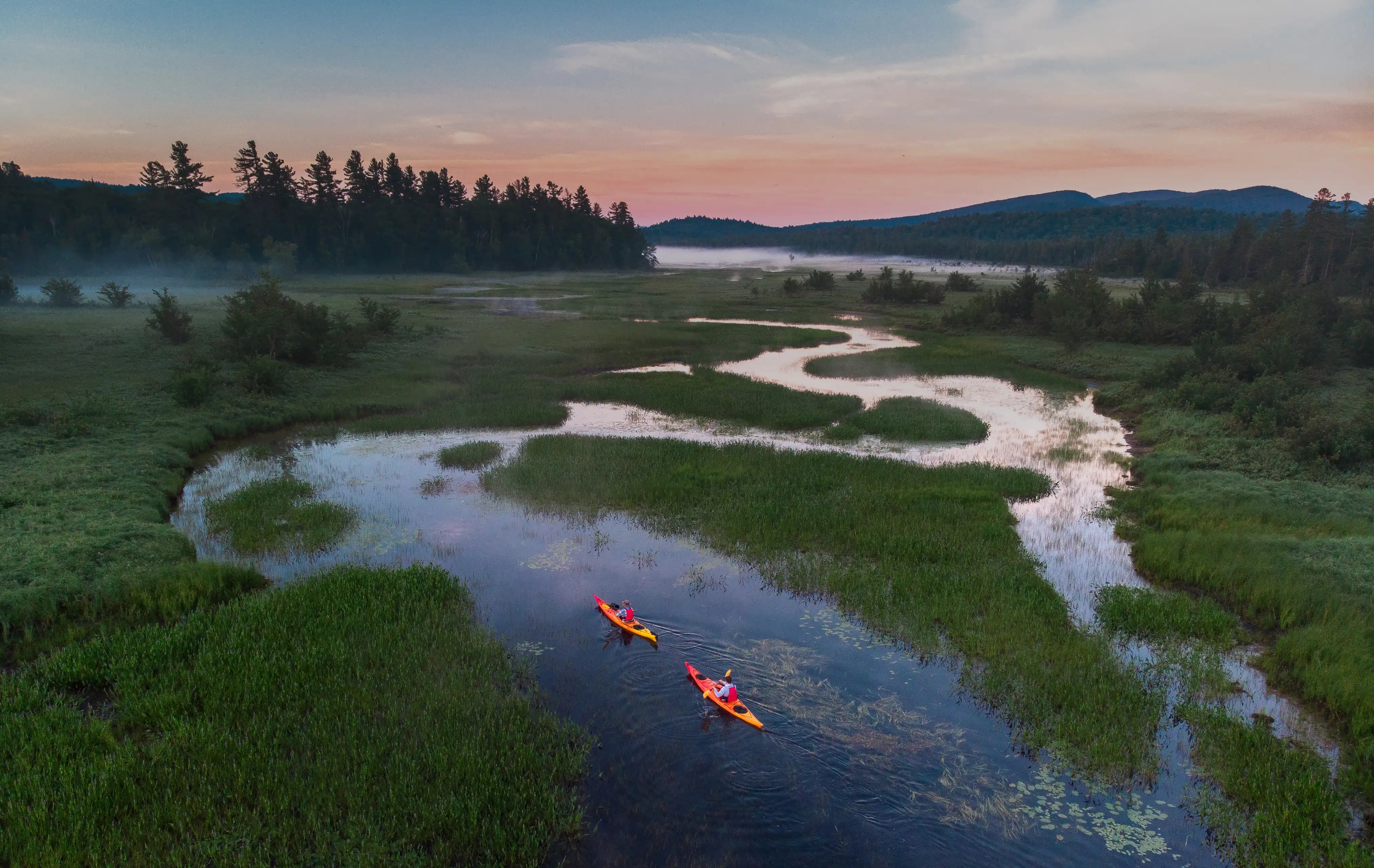 Two kayakers paddling at sunset